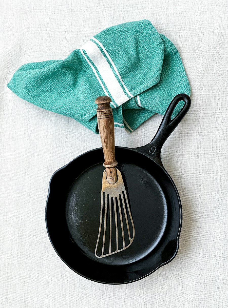Gietijzeren pan met een vork en een theedoek op tafel
